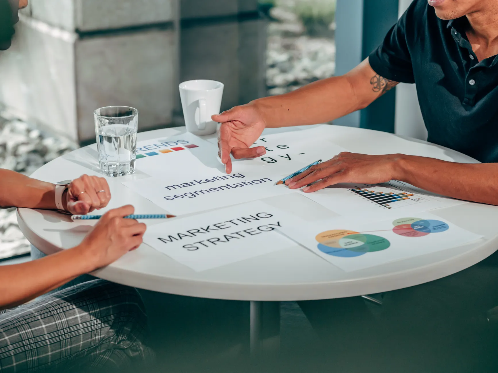Two adults in an office discussing marketing strategy around a round table.